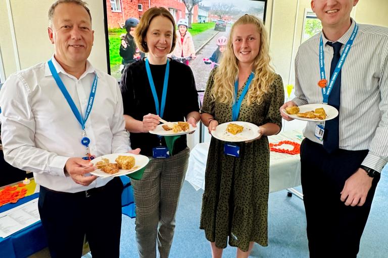 Four council employees holding paper plates with food on