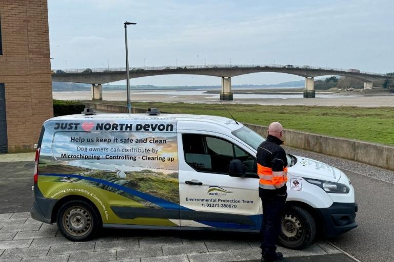 Dog warden on patrol in Barnstaple standing next to van and Barnstaple Bridge