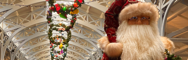 Christmas at Barnstaple Pannier Market. Wreaths hanging from ceiling and large Santa in foregound